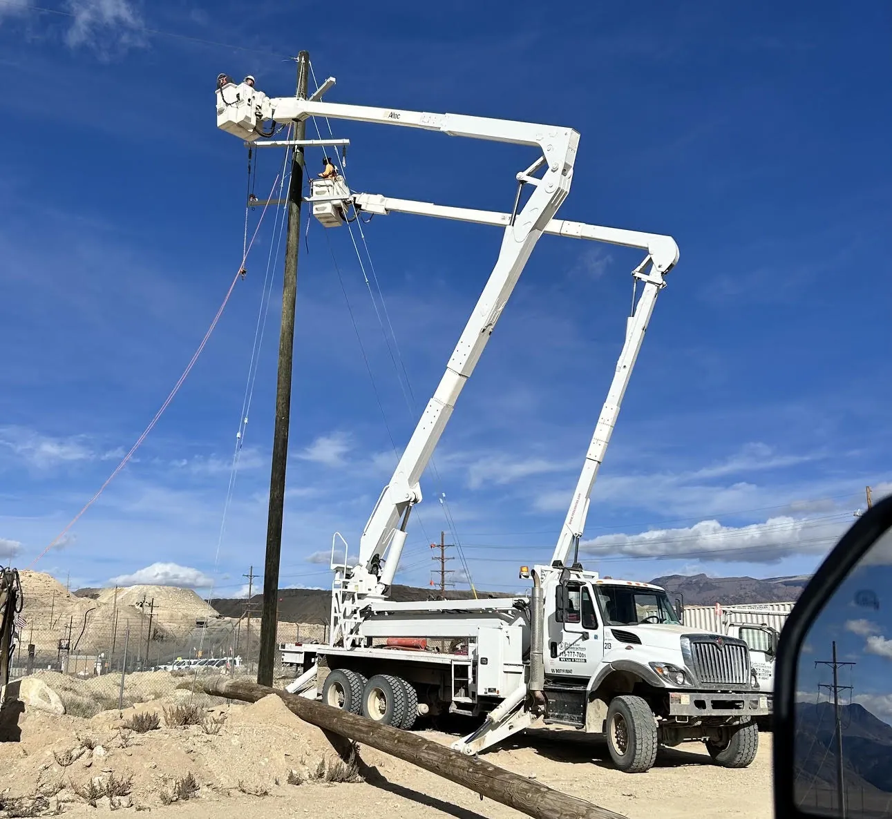 Pole Line Contractors crew working from elevated buckets beside a utility pole.